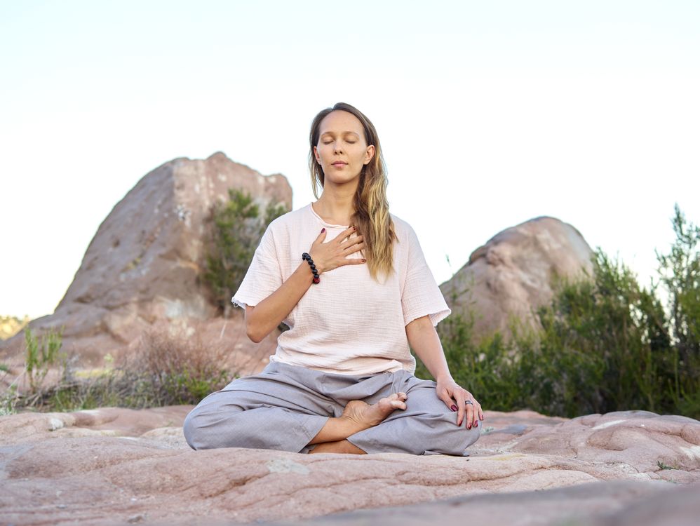 Mujer meditando con los ojos cerrados en un ambiente sereno y pacífico
